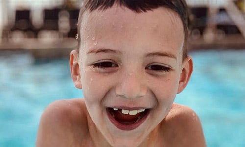 little boy laughing in pool