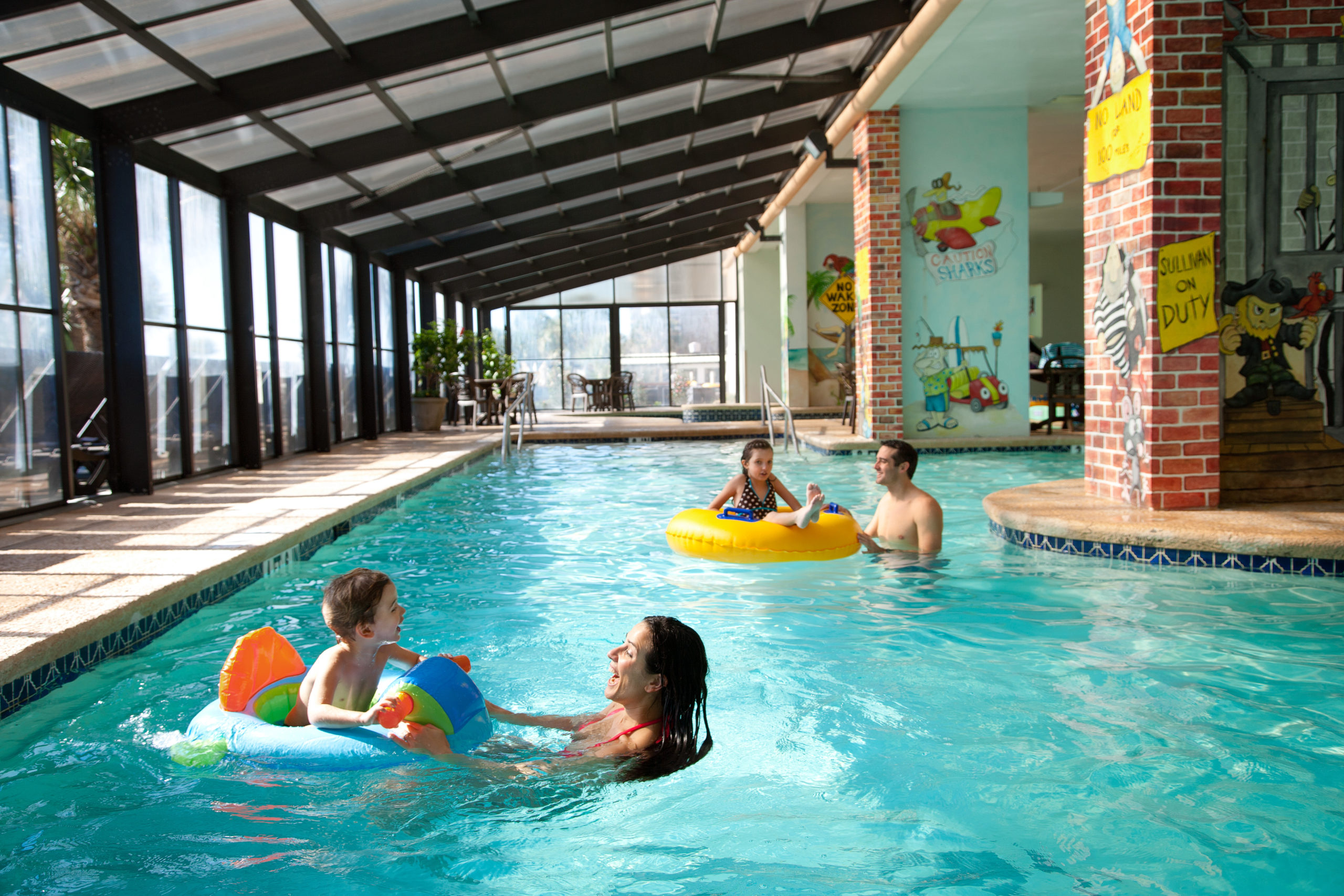 A group of people enjoying the indoor pool with colorful floats.