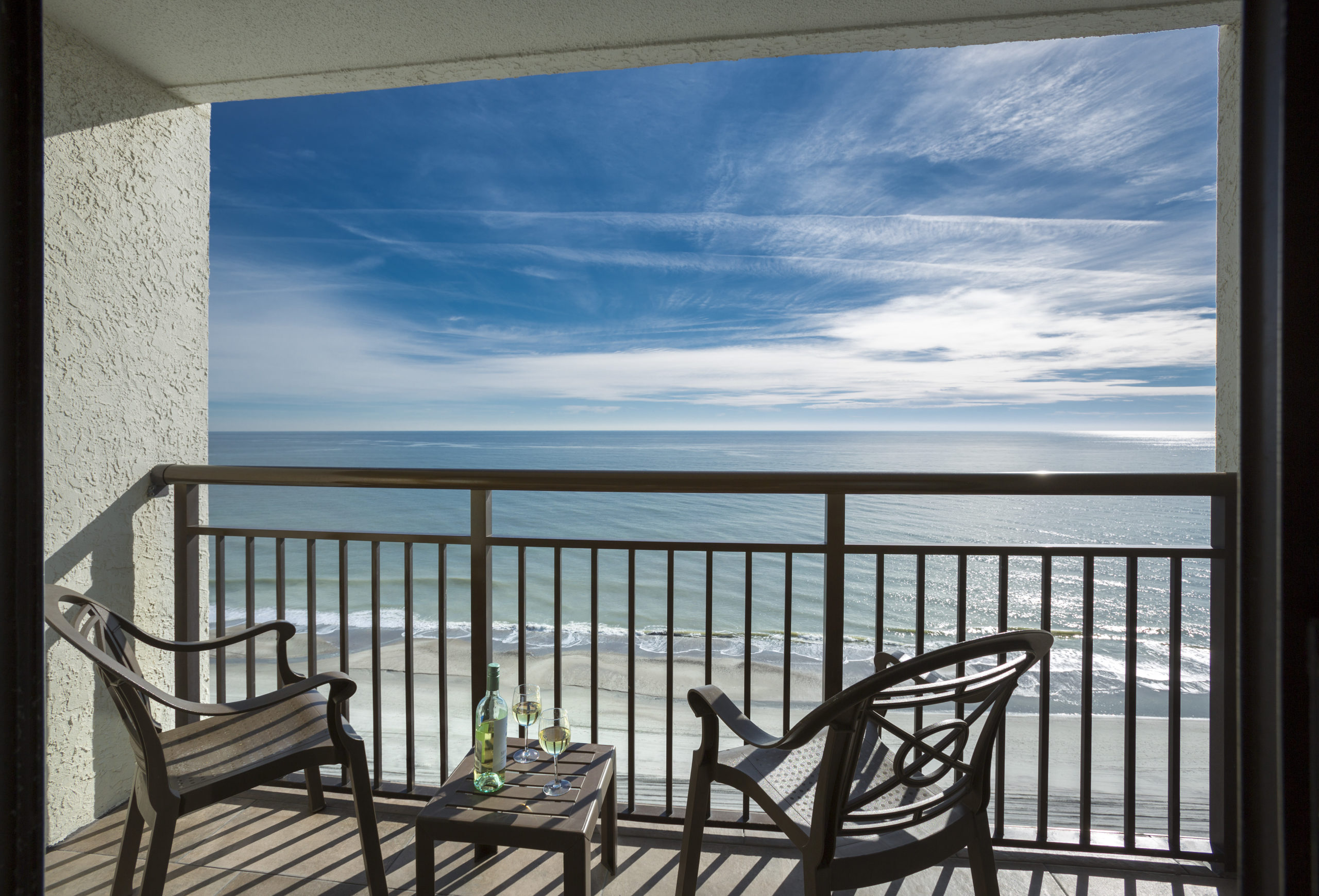 A balcony with a view of the ocean and two chairs
