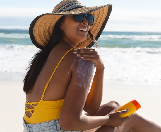 Smiling woman on beach holiday using sunscreen cream. healthy outdoor leisure time by the sea.