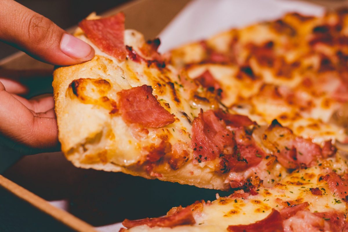 Hand grabbing pepperoni pizza