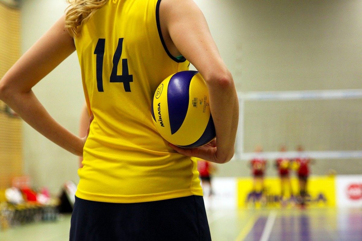 Girl in yellow jersey holding volleyball
